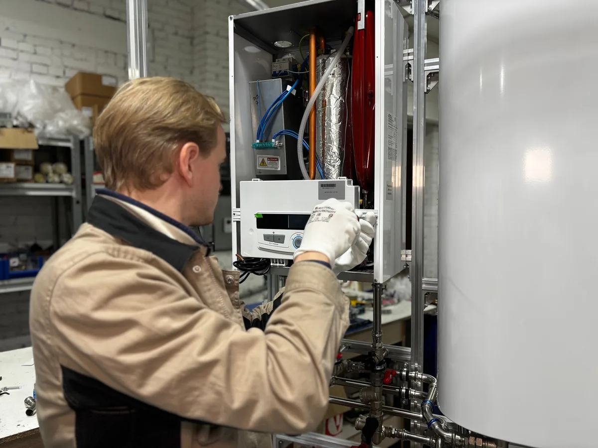 HVAC technician in work gloves servicing a wall-mounted heating system